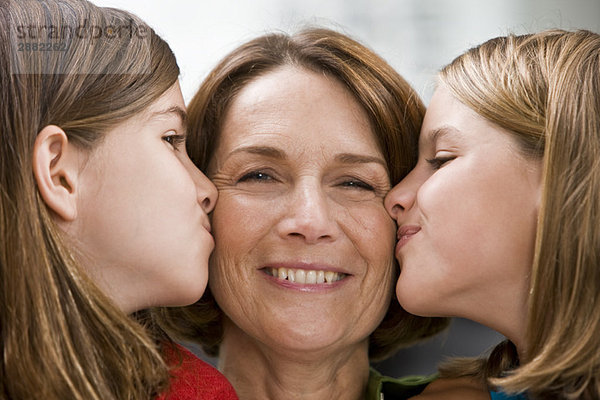 Nahaufnahme von zwei Mädchen  die ihre Großmutter küssen