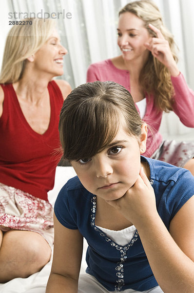 Mädchen sieht traurig aus  wenn ihre Eltern hinter ihr sitzen.