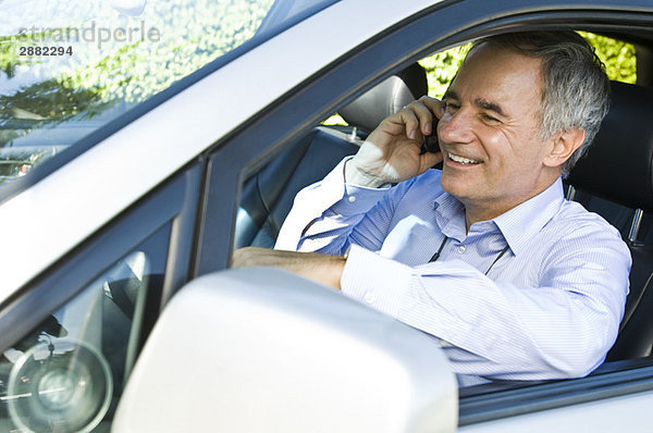 Mann sitzt im Auto und redet auf dem Handy
