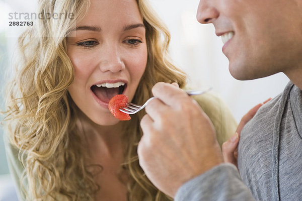 Mann füttert seine Frau mit Erdbeeren