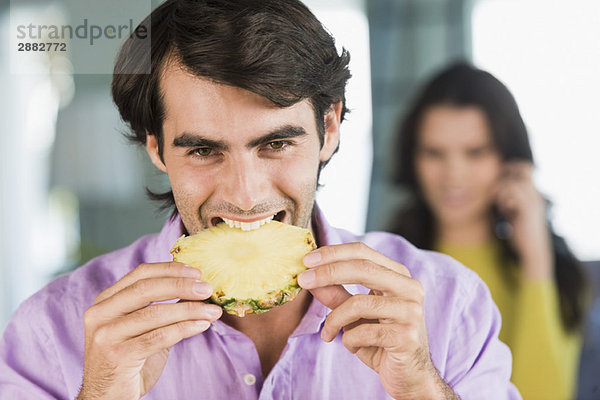 Mann beim Essen einer Ananasscheibe