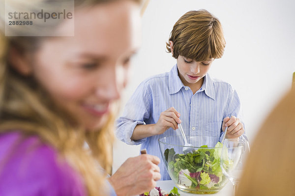 Junge mischt Salat in einer Schüssel