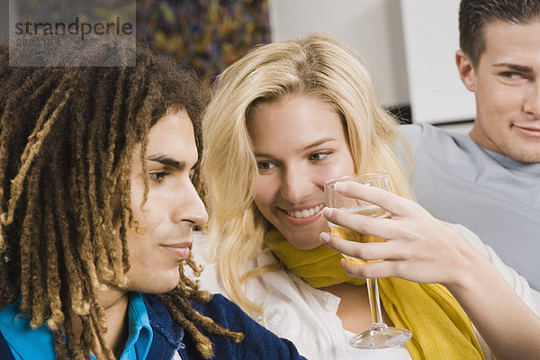 Frau hält ein Glas Wein und sitzt mit ihren Freunden zusammen