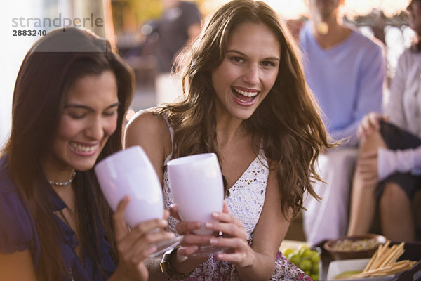 Zwei Frauen  die mit ihren Freunden im Hintergrund trinken.