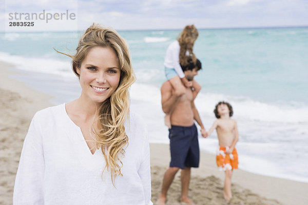 Frau lächelt mit ihrer Familie im Hintergrund