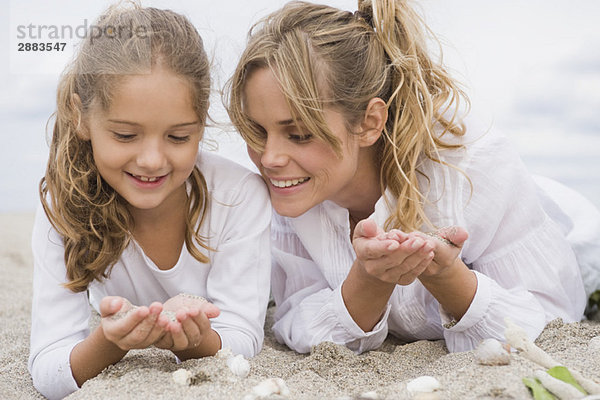 Frau mit ihrer Tochter am Strand liegend