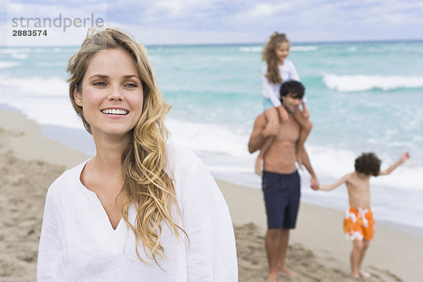Frau lächelt mit ihrer Familie im Hintergrund