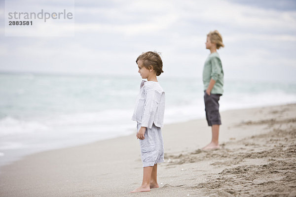 Zwei Jungen  die am Strand stehen.