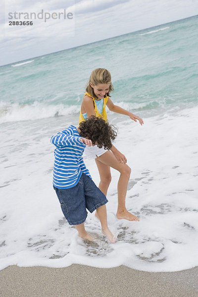 Junge spielt mit einem Mädchen am Strand