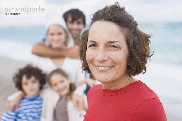 Frau lächelt mit ihrer Familie am Strand
