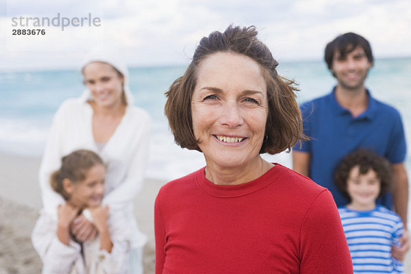 Frau lächelt mit ihrer Familie am Strand