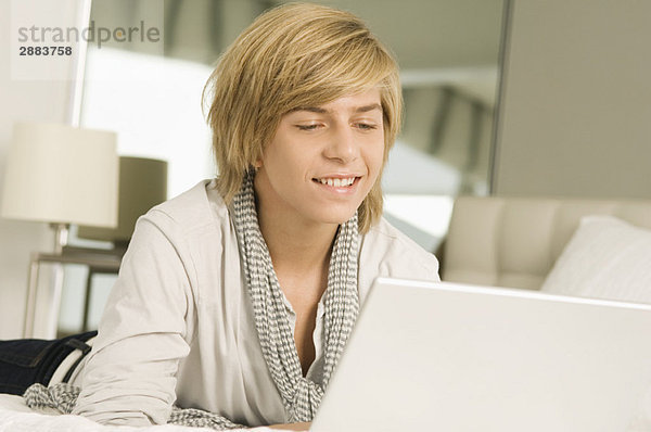 Teenager-Junge arbeitet an einem Laptop und lächelt