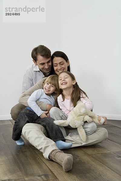 Eine vierköpfige Familie  die lacht und sich umarmt.