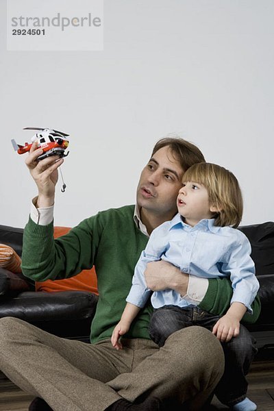 Ein Vater und Sohn spielen mit einem Spielzeughubschrauber.