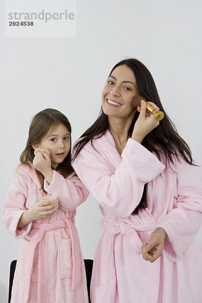 Mutter und Tochter in rosa Bademänteln mit Make-up