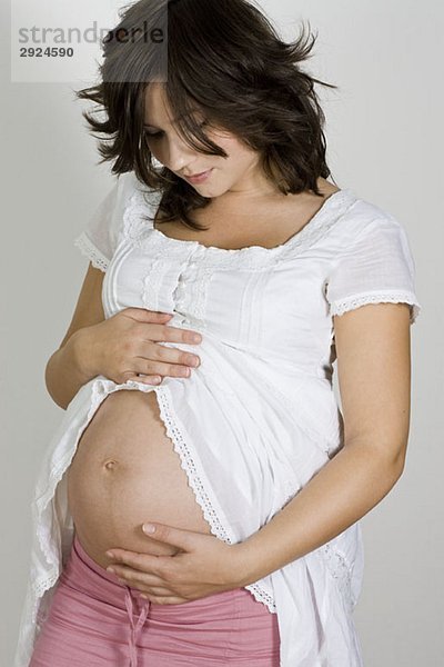 Eine schwangere Frau  die ihren Bauch wiegt.