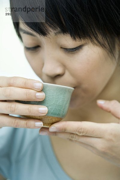 Eine Frau  die aus einer Teetasse trinkt.