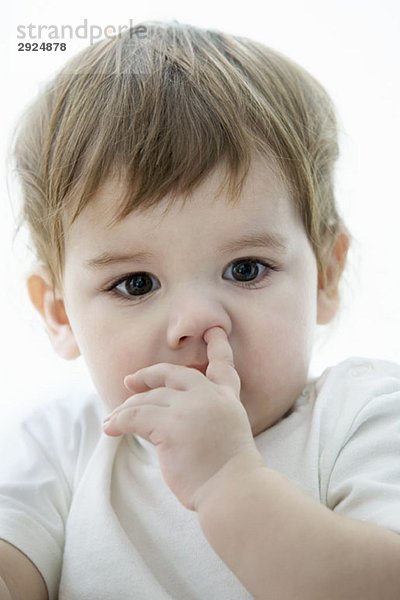 Ein kleiner Junge mit einem Finger in der Nase.