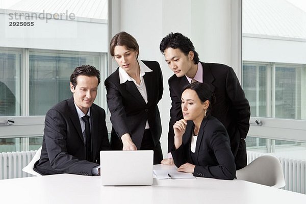 Vier Geschäftsleute in einer Besprechung mit einem Laptop