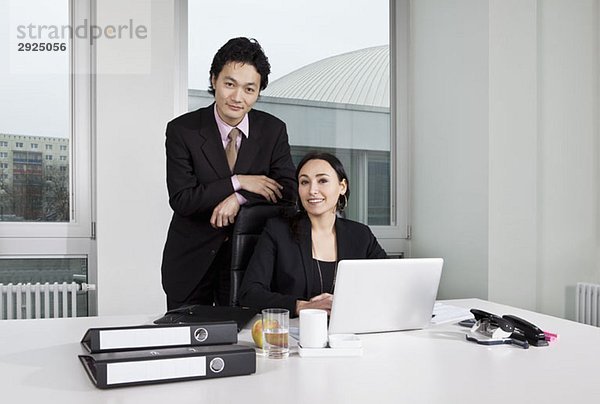 Ein Geschäftsmann und eine Geschäftsfrau  die auf einen Laptop schauen.