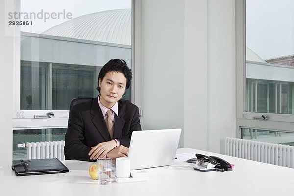 Porträt eines Geschäftsmannes  der an seinem Schreibtisch sitzt