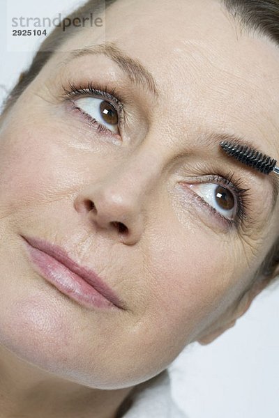 Eine Frau  die eine Schminkpinsel auf ihren Augenbrauen benutzt.