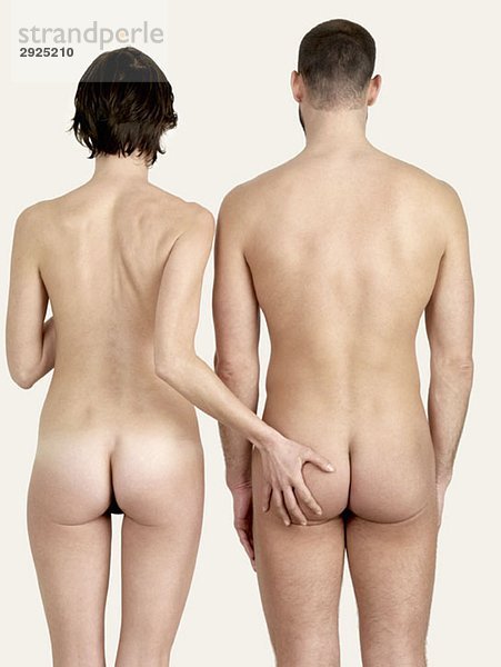Rückansicht einer nackten Frau  die den Hintern eines nackten Mannes berührt.