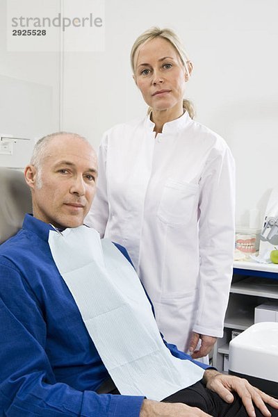 Eine Zahnarzthelferin und ein Patient in einem zahnärztlichen Untersuchungsraum