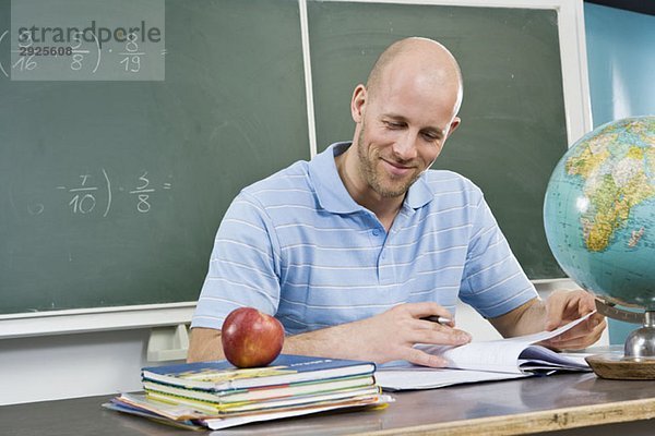 Ein Lehrer  der am Schreibtisch sitzt.