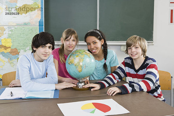 Schüler sitzen an einem Tisch mit Weltkugel