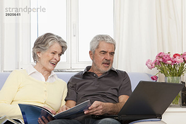 Eine ältere Frau und ein älterer Mann  die einen Laptop benutzen.