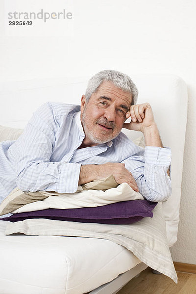 Ein älterer Mann  der auf einer Couch liegt.