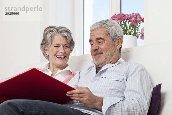 Ein älteres Paar  das zusammen durch ein Buch schaut.