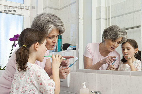 Eine Großmutter  die ihrer Enkelin beibringt  wie man Zähne putzt.