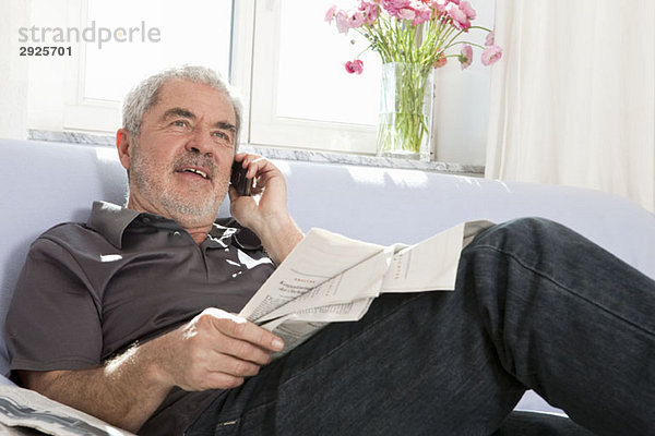 Ein älterer Mann  der auf einem Handy spricht.