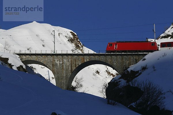 Glacier Express Zug über die Brücke über verschneite Berge  Graubünden  Schweiz