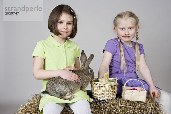 Zwei Mädchen mit einem Kaninchen und einem Entlein im Korb