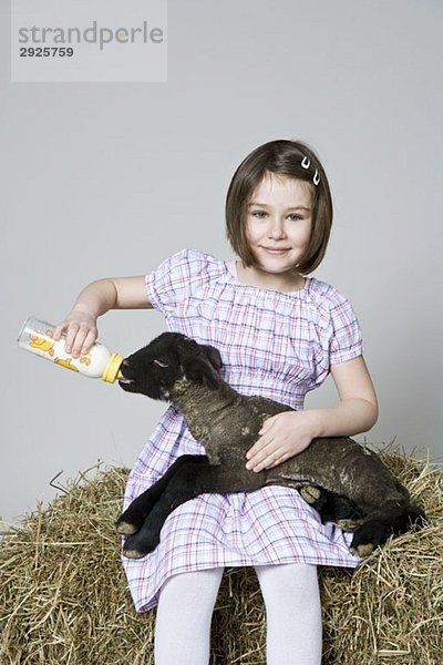 Ein Mädchen füttert ein schwarzes Lamm  Studioaufnahme