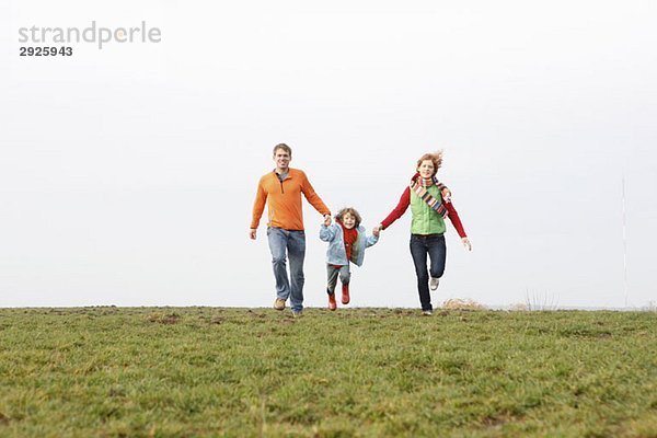 Eine junge Familie  die zusammen in einem Park läuft.