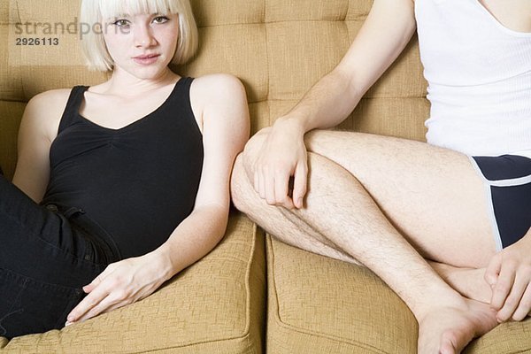 Ein junges Paar  das zusammen auf einem Sofa sitzt.