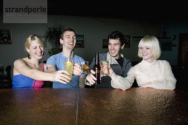 Vier Freunde stoßen an einer Bar auf einen Drink an.