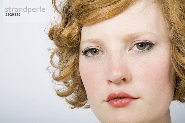 Porträt einer jungen erwachsenen Frau mit lockigen roten Haaren