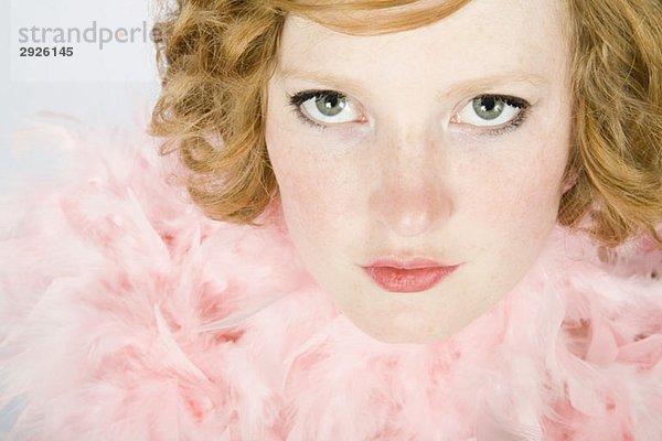 Porträt einer jungen Frau mit rosa Federboa
