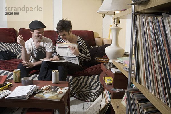 Zwei junge Männer  die sich auf einem Sofa Rekorde ansehen.