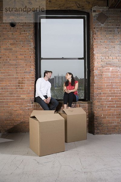 Ein Paar sitzt auf der Fensterbank mit Pappkartons