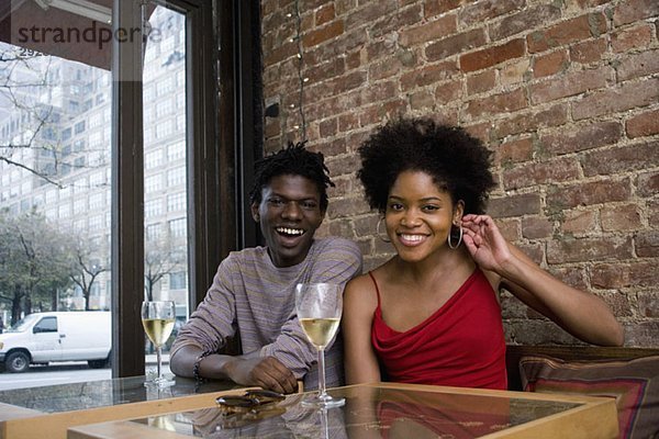 Ein junges Paar sitzt in einem Restaurant mit Gläsern Weißwein.