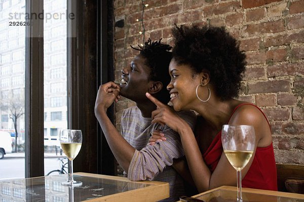 Ein junges Paar sitzt in einem Restaurant mit Gläsern Weißwein.