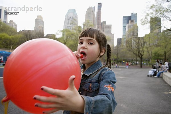 Ein junges Mädchen sprengt einen Ballon im Central Park  New York City.