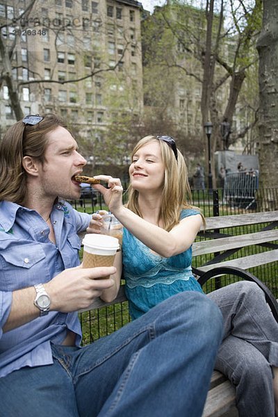 Eine Frau füttert einen Mann mit einem Keks in einem Park  Central Park  New York City.