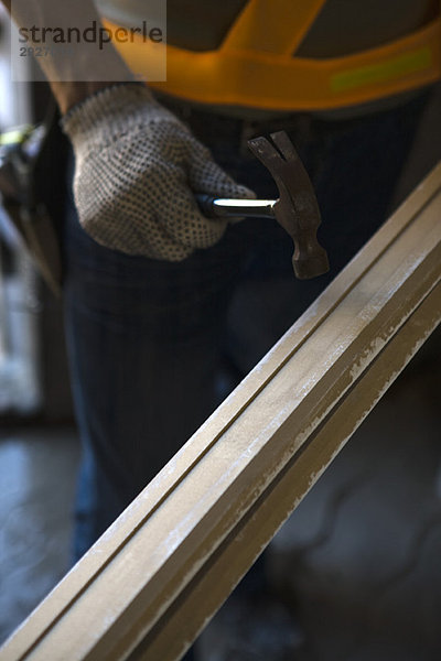 Arbeiter hält Hammer gegen Holz